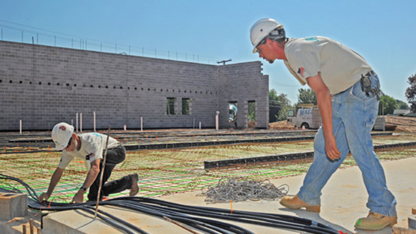 Two workers installing foundation materials at a construction site.